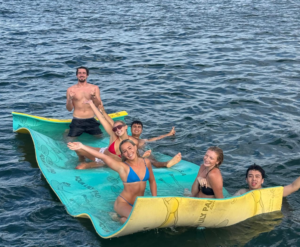 Friends relaxing on colorful floating lily pads during a San Diego Bay anchor and swim cruise