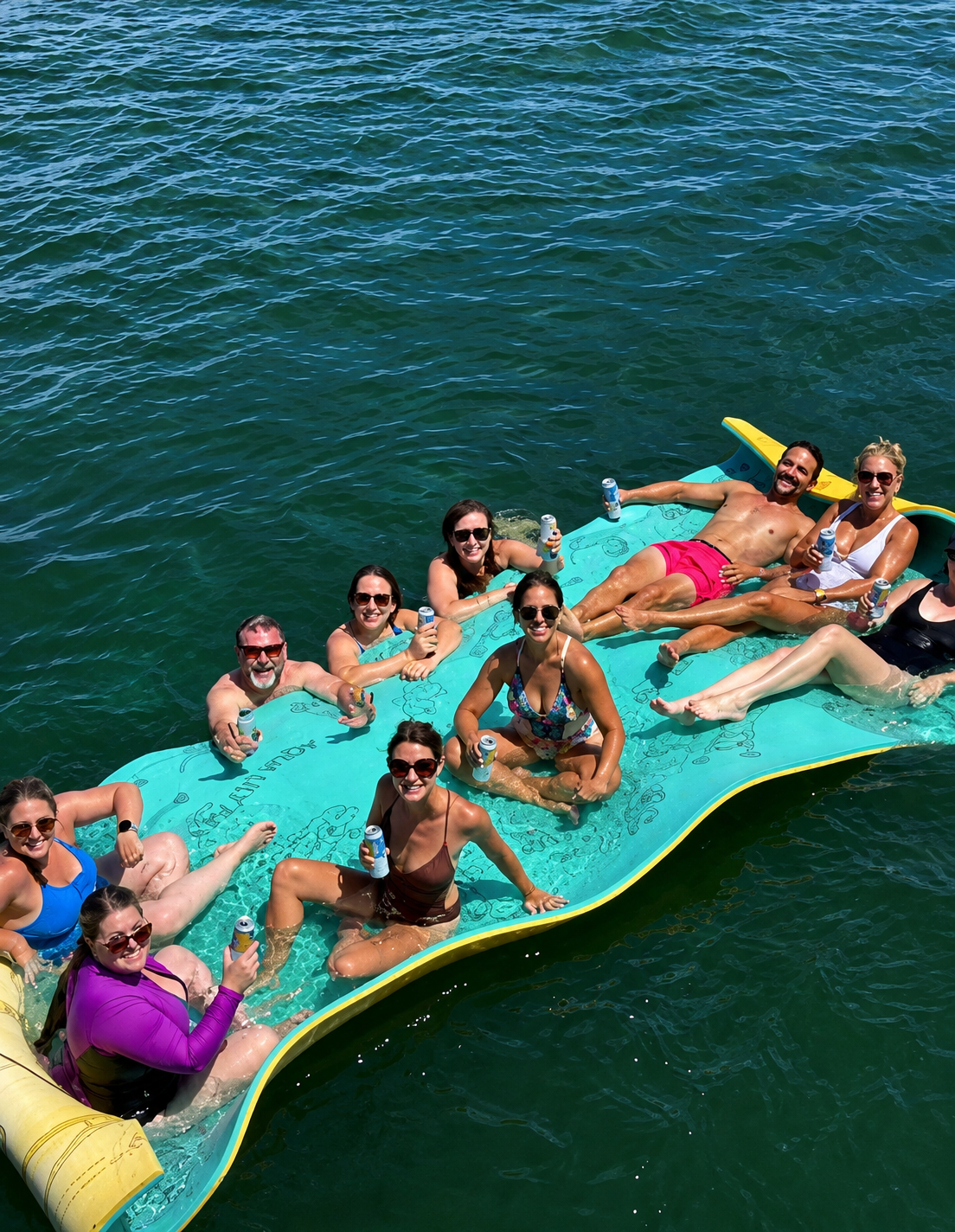 Guests relaxing together on a floating lily pad during an anchor and swim cruise on San Diego Bay