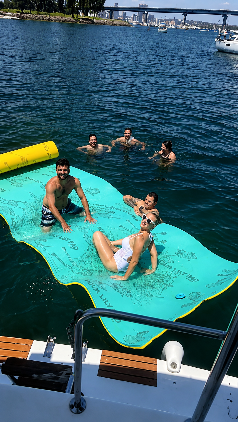 Guests swimming and relaxing on a floating lily pad near Coronado Bridge during a San Diego Bay cruise