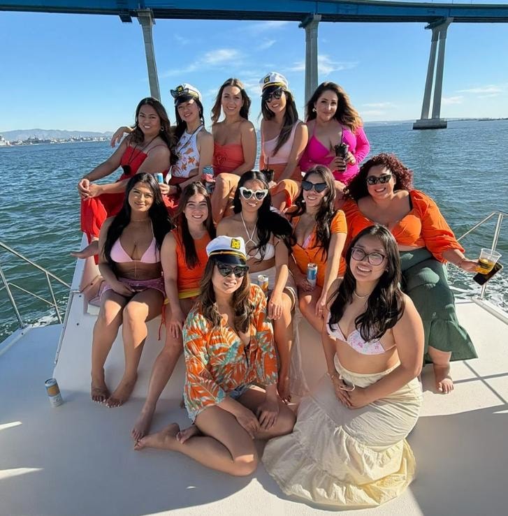 Large bachelorette group in captain hats celebrating on private yacht bow under Coronado Bridge