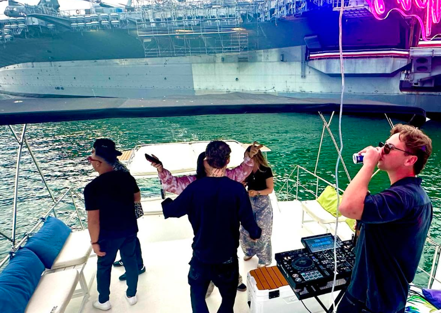 Guests dancing on private party boat near USS Midway with neon lights — San Diego DJ yacht party