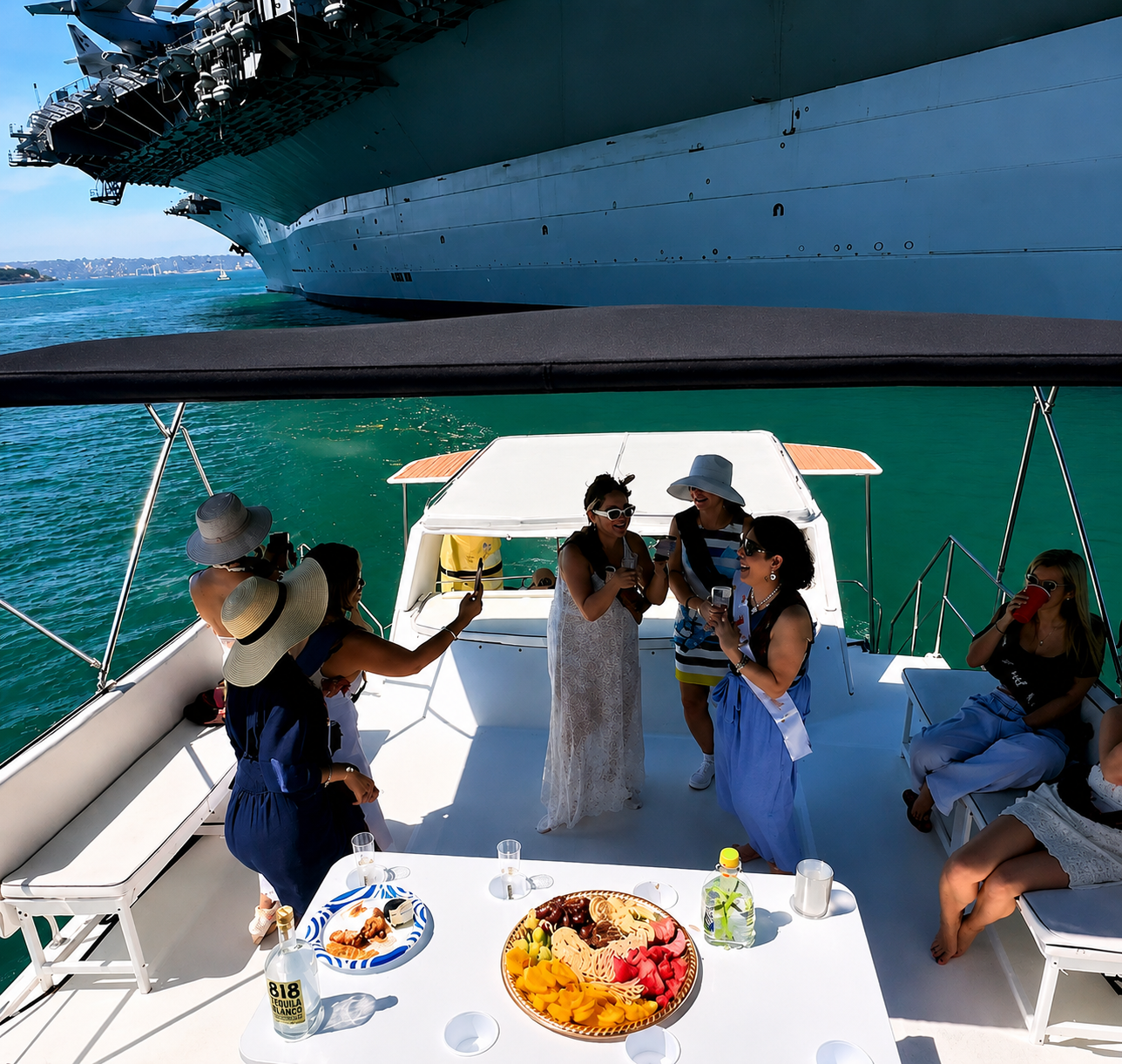 San Diego yacht charter — women socializing on private party boat deck near USS Midway with charcuterie spread