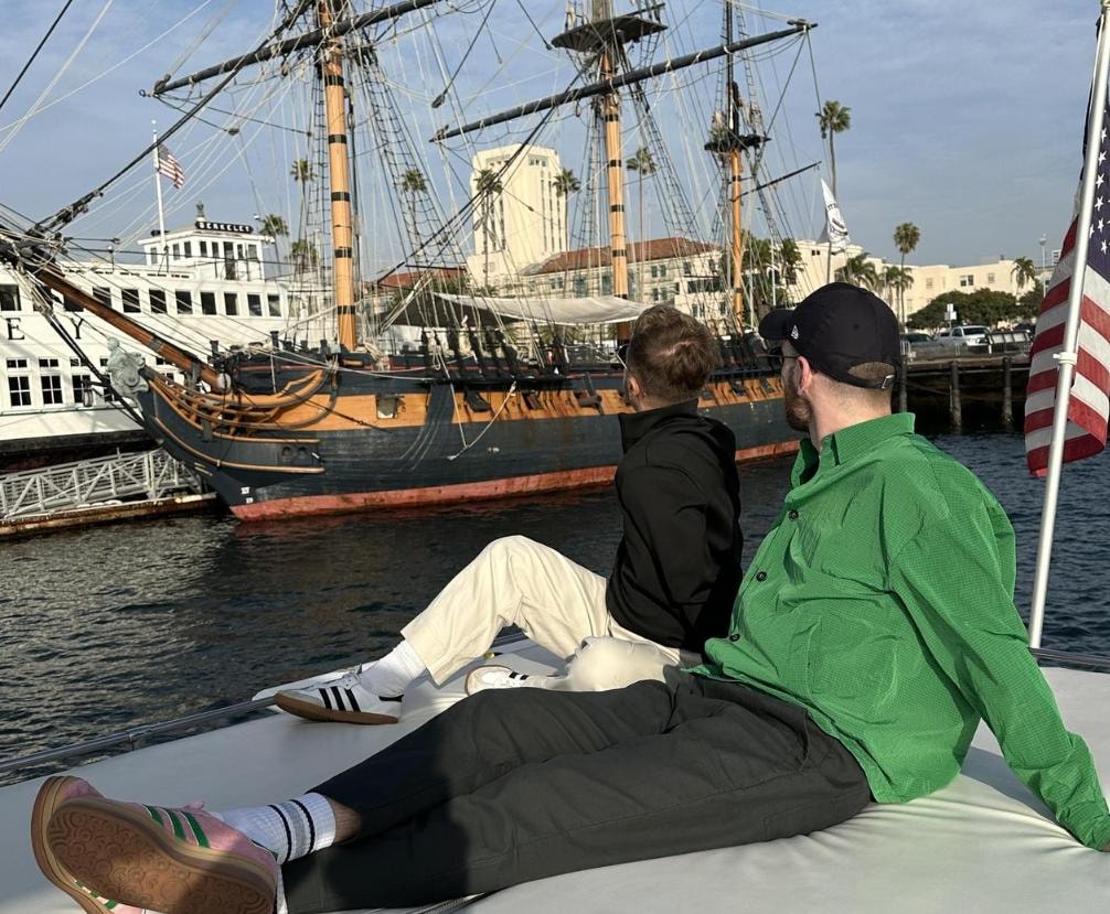 Two guests relaxing on private yacht bow viewing the Star of India tall ship on San Diego Bay