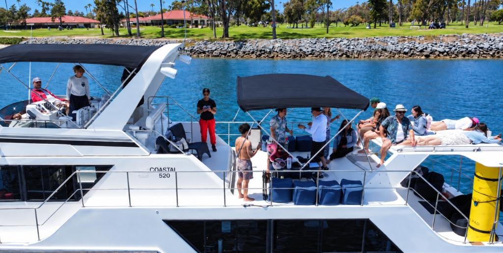 Large group relaxing on the deck of a private yacht charter anchored in San Diego Bay — bay cruise