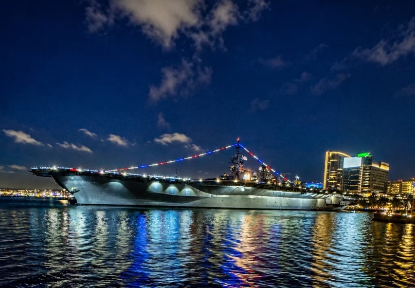 San Diego Bay night cruise — USS Midway aircraft carrier lit up at night viewed from private yacht charter