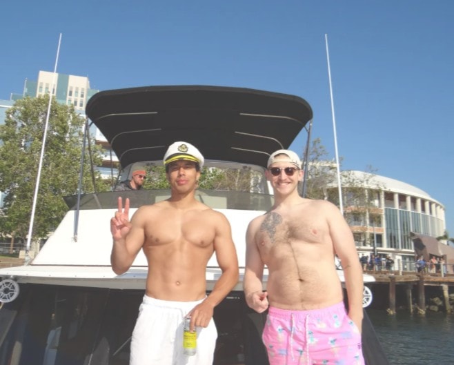 Private boat rental San Diego — guests posing in front of Paradise Party Yacht at Sunroad Marina