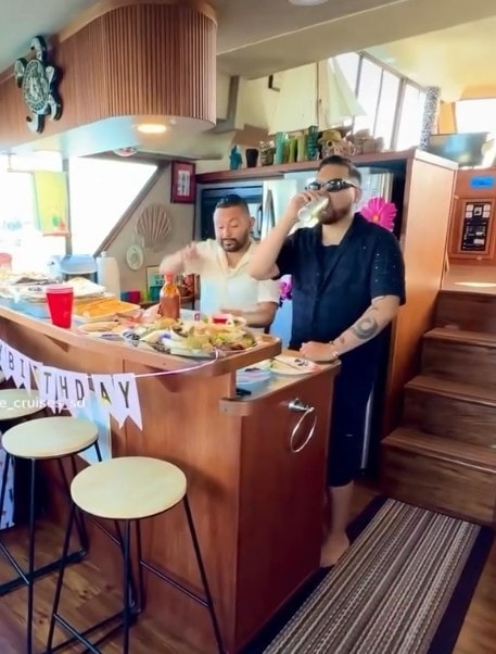 Birthday party boat San Diego — guests at private yacht cabin bar with food and birthday banner