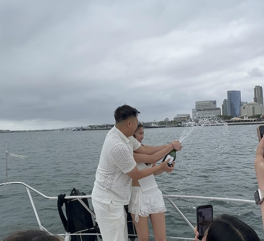 Couple popping champagne on San Diego Bay private yacht charter — celebration on the water
