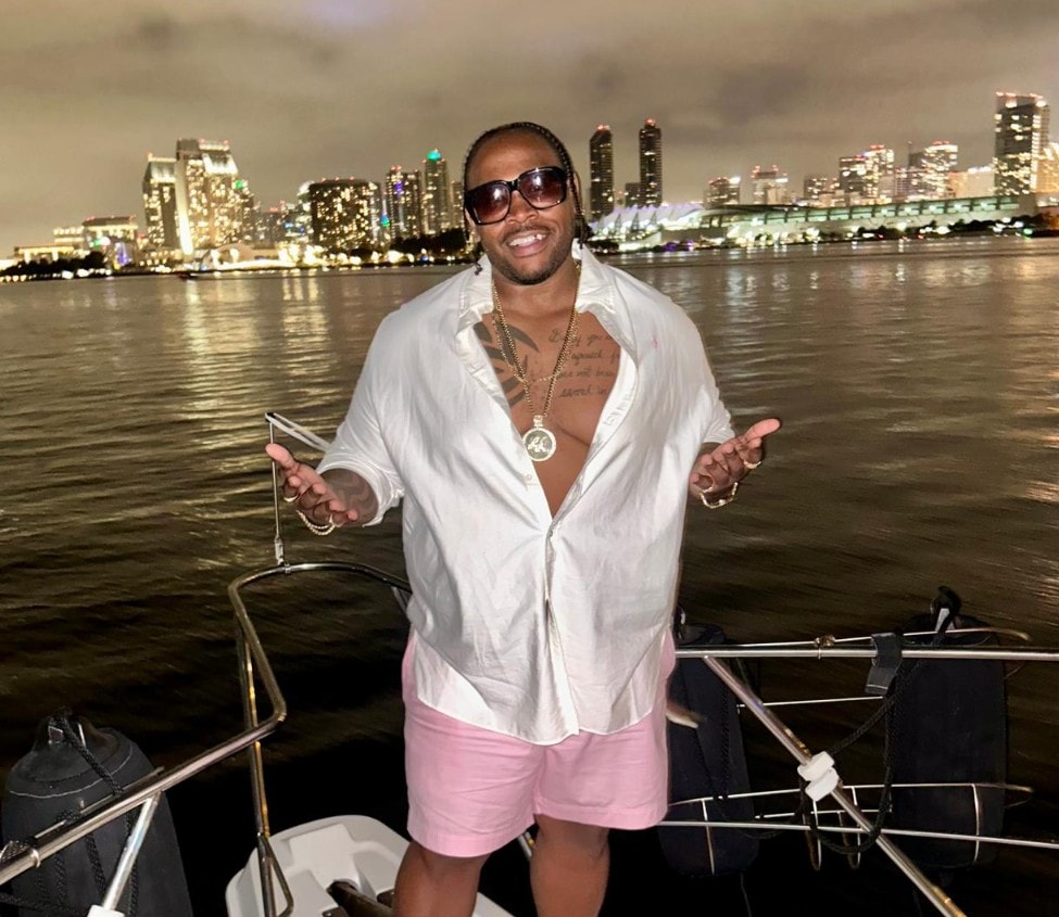San Diego night cruise — man celebrating on private party boat with glowing downtown skyline backdrop