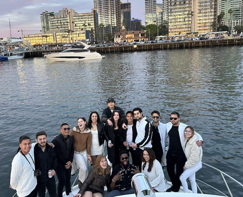 San Diego party boat rental — large group of friends celebrating at dusk on private yacht charter on the bay