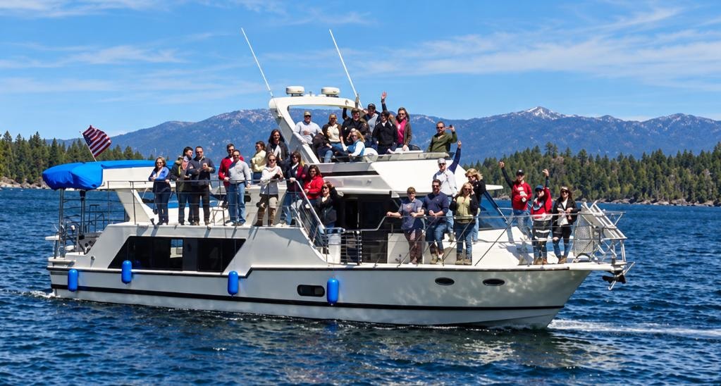 Large group of guests aboard The Party Boat cruising Lake Tahoe with mountain backdrop